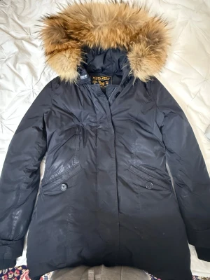 Woolrich jacka - Säljer min woolrich jacka då den inte är min stil längre! Har använt den ett par gånger men den är gott skick, på bilden ser man ”märken” men det är bara reflektionen av ljuset 😅 Jackan är quiltad på insidan så man behöver ingen tjock tröja under. Pälsen är äkta därav pris! Priset kan diskuteras vid snabb affär💕