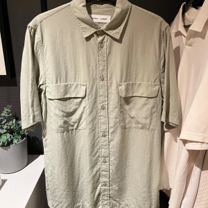 Ljusgrön kortärmad skjorta Samsøe Samsøe - Ljusgrön skjorta från Samsøe Samsøe med korta ärmar och två stora bröstfickor. Skjortan har klassisk krage och knappar hela vägen framtill. Perfekt att bära öppen över en t-shirt. Nypris 1299kr