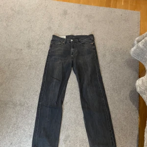 Svarta relaxed fit jeans från H&M - Säljer ett par svarta jeans från H&M i relaxed fit med raka ben och klassisk femficksdesign. Jeansen har en mörk tvätt och är tillverkade i bomullsmaterial. Perfekta för en chill och avslappnad stil.