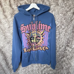 Blå Sublime hoodie med tryck, M - Blå hoodie med dragkedja från Divided. Huva med snörning och kängurufickor. 