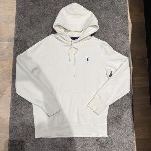 Vit Ralph Lauren Hoodie - Säljer denna riktigt feta raffe Hoodien i bra skick. Enda defekten är en liten fläck som knappt syns vid användning (bild 5). Hoodien är äkta och kan bevisas med QR kod vid nacken. Pris kan diskuteras vid snabb affär!