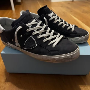 Philippe Model blåa sneakers mocka - Snygga mörkblåa( de är blåa men ser mörkare ut på bilderna) Philippe Model sneakers i mocka med vita snören och vit häl. Klassisk låg modell med rund tå, platt sula och diskret logga på sidan. Perfekta för dig som gillar stilrena och trendiga skor med exklusiv känsla. Storlek 46. Använda fåtal gånger mest i skolan låda tillkommer pris går att diskutera vid snabb affär 
