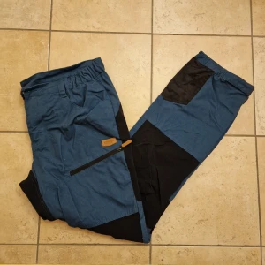 Friluftsbyxor - Blå-svarta outdoor/snickerboa byxor. Mått: Ben - 110 cm, Midja (ihopdraget läge med resår) 50 cm. 