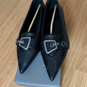 Hermine Mules skor från Vagabond med spänne - Säljer ett par skitsnygga spetsiga ballerina skor från Vagabond. Är i storlek 38. Säljer då jag köpte fel storlek. Är helt nya! Aldrig använda och originalkartong medföljes  Nypris: 1299kr