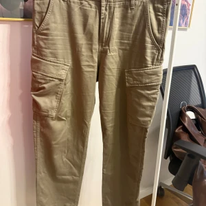 Levi's XX Cargo byxor i beige bomull - Snygga Levi's XX Cargo byxor i beige bomull med flera praktiska fickor på sidorna och bak. Klassisk cargomodell med avslappnad passform och bälteshällor. Perfekta för en chill och streetig stil.