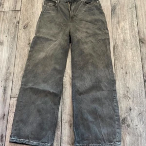 Gråa Jeans - Gråa jeans från H&M i storlek 34 med raka ben och hög midja. Jeansen har klassisk femficksdesign, orangea sömmar och är tillverkade i ett robust jeanstyg. Snygga till sneakers eller boots för en chill look.