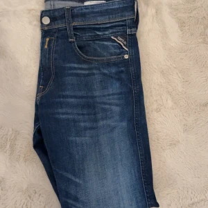 Replay Anbass blå jeans slim fit - Snygga blå Replay Anbass jeans med slim fit och klassisk femficksdesign. Storlek W29-L32. Perfekta för dig som gillar en modern och stilren denimstil.