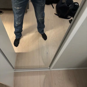 Replay Grover jeans blå, storlek 32/34 - Säljer ett par Replay Grover jeans i blå denim med slitna detaljer och distressed look. Klassisk femficksmodell med raka ben och normal passform. Märket Replay syns tydligt på etiketten. Perfekta för dig som gillar en avslappnad och trendig stil.