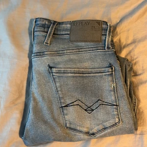 Replay Anbass ljusblå jeans, stl 30 - Snygga ljusblå Replay Anbass jeans med klassisk femficksdesign och diskreta slitningar. Jeansen har normal passform och är tillverkade i mjukt denimtyg. Märkesdetaljer på bakfickan och vid myntfickan ger en schysst look.