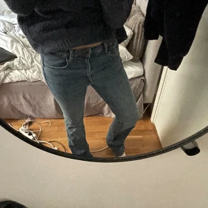 Jeans - Säljer ett par klassiska blå jeans med bootcut-snitt och normal passform. Jeansen har fem fickor, hällor för bälte och stängs med dragkedja och knapp. Perfekta för dig som gillar en tidlös look med lite utsvängda ben.