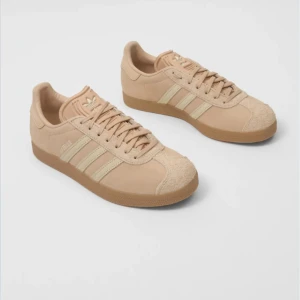 Intresekoll Beige Adidas Gazelle sneakers - Snygga beige Adidas Gazelle sneakers med klassiska tre ränder på sidan och gummisula. Ovandelen är i mocka och detaljerna är ton-i-ton. Perfekta för en clean och stilren look. I strlk 38 oanvända  nypris 1300