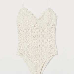Vit spets body från hm - Superfin vit body med tunna axelband och v-ringning. Hela toppen är täckt av ett detaljerat blommigt spetsmönster som ger en romantisk och somrig vibe. Perfekt att styla med jeans eller kjol för en fräsch look💗💗🫰🫰