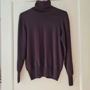 Mörkbrun polotröja från Lui & Lei - Säljer en mörkbrun stickad polotröja från Lui Lei med hög krage och långa ärmar. Storleken känns som M.