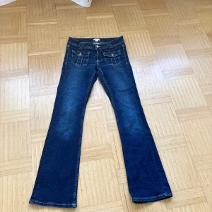 Mörkblå bootcut jeans med fickdetaljer lågmidja  - Snygga mörkblå jeans med bootcut och lågmidja.