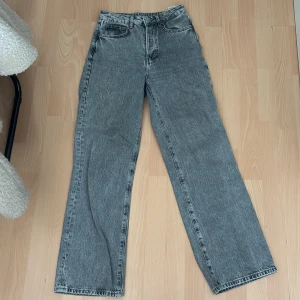 Grå wide jeans från Never Denim - Säljer ett par gråa wide leg jeans från Never Denim. Modellen är regular wide med hög midja och raka, breda ben. Klassisk femficksdesign och snygg tvättad grå färg. Perfekta för dig som gillar en avslappnad och trendig look.