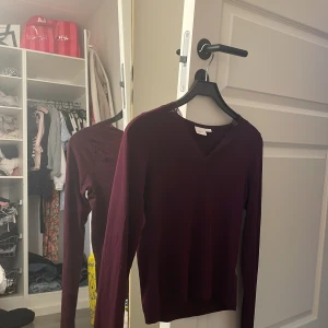 Vinröd långärmad topp med spets Gina Tricot - Aldrig använd. Slutsåld på Gina.    Vinröd långärmad topp från Gina Tricot med v-ringning och snygga spetsdetaljer runt halsen. Perfekt för dig som vill ha en enkel men ändå elegant look. Mjuk och skön, passar till många olika outfits.