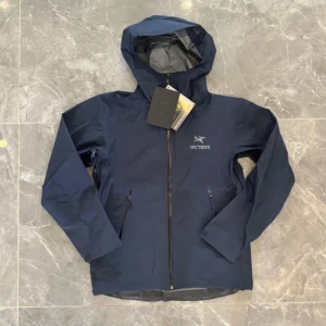 Mörkblå Arc'teryx vindjacka Gore-Tex - Snygg mörkblå vindjacka från Arc'teryx med huva och vattentätt Gore-Tex-material. Jackan har dragkedja framtill, två sidofickor med dragkedja och stilren logga på bröstet. Perfekt för dig som gillar outdoor och vill ha en jacka med clean look.