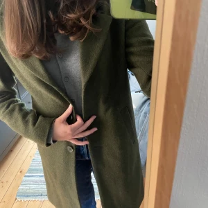 Grön kappa  - Knälång mörkgrön höst/vinterkappa, från Selected Femme. Säljer då den är något kort i ärmen på mig. Sparsamt använt, bara haft på mig några enstaka gånger. Köpte den för 1089kr men säljer nu för 400 (sänkt från 450) då den bara tar plats i garderoben. Storlek 36 men passar mig som brukar ha 36/38/S/M. Perfekt till hösten/vintern💚