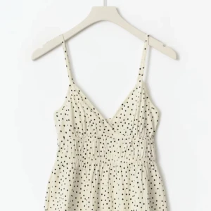 Prickig blus - Supersöt blus i ljus beige med svarta prickar, smala axelband och v-ringning. Blusen har en lätt rynkad midja och är perfekt för varma dagar. Tunn och luftig känsla, passar dig som gillar en avslappnad men trendig stil. Man kan även spänna åt banden ❤️