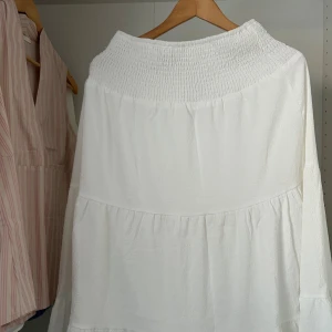 Vit långkjol från SHEIN med volanger - Superfin vit långkjol från SHEIN i storlek M. Kjolen har bred smock i midjan och flera volanglager som ger en flowy och luftig känsla. Perfekt för dig som gillar en romantisk och avslappnad stil.