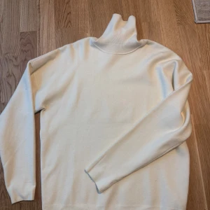 Vit polotröja från Zara - Klassisk vit polotröja från Zara i mjukt material. Tröjan har lång ärm, hög polokrage och en enkel, stilren design som passar perfekt till lager-på-lager. Snygg att styla med jeans eller kjol för en clean look. Ej hår på tröjan de är materialet från klädhängaren som har fastnat på plagget. Går bort i tvätten. 