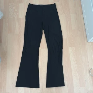 Svarta bootcut kostymbyxor Gina Tricot - Svarta kostymbyxor från Gina Tricot i storlek 36. Byxorna har bootcut-modell med utsvängda ben, hällor för bälte och diskreta fickor både fram och bak. Snygg och stilren look som passar till många olika outfits.