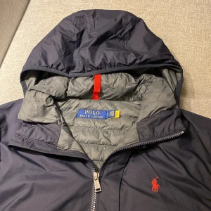 Mörkblå Jackafrån Polo Ralph Lauren - Säljer nu min Ralph lauren jacka då den har blivit för liten. Det är storlek S men sitter lite oversize så skulle säga att det är M. Den är perfekt nu inför hösten och vintern då den håller kylan bra. Den är köpt ifrån Ralph laurens egna butik för nypris på 2600kr om jag inte minns fel. Hör av er vid frågor eller intresse!