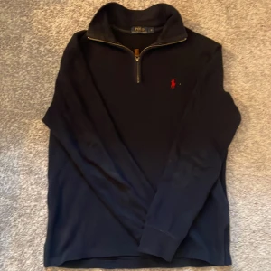 Half zip tröja från Polo Ralph Lauren - Svart långärmad tröja från Polo Ralph Lauren med klassisk röd logga. Tröjan har en hög krage och half zip-dragkedja med läderdetalj. Perfekt för lager-på-lager och stilren look. Skit bra skick och helt perfekt nu till höst o vinter, priset är inte hugget i sten 💯 