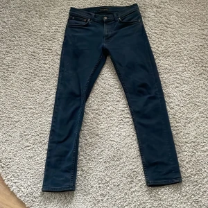 Mörkblå skinny jeans från Nudie - Snygga mörkblå skinny jeans från Nudie med klassisk femficksdesign och diskret broderad bakficka. Jeansen har smal passform och är tillverkade i stretchig bomullsdenim för en bekväm känsla hela dagen.