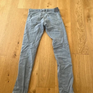 Replay Hyperflex Anbass grå jeans - Säljer ett par grå Replay Hyperflex Anbass jeans med klassisk femficksdesign och raka ben. Jeansen är tillverkade i stretchigt material för extra komfort och har en snygg, modern passform. Perfekta för dig som gillar stilrena och bekväma jeans. Köpt för 999kr 