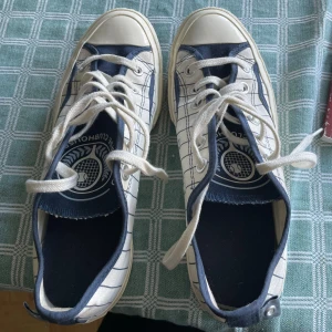 Randiga Converse All Star sneakers - Snygga Converse All Star sneakers i vitt tyg med marinblå ränder och detaljer. Skorna har klassisk rund tå, vita snören och gummisula. Insidan har ett coolt tryck med tennistema. Skorna är använda ett par fåtal gånger och är i fint skick! Skosnörena är lite slitna och behöver förmodligen bytas.