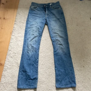 Blå jeans från Calvin Klein - Säljer ett par klassiska blå jeans från Calvin Klein med raka ben / bootcut ben. Jeansen har fickor, snygga sömmar och ikonisk CK-logga på knappen och bak på linningen. Perfekta för en avslappnad och tidlös look.