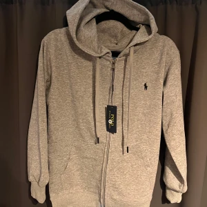 Grå full-zip hoodie från ralph lauren - Säljer min ralph lauren full-zip som är helt ny fick i present för ungefär 1 vecka sen men den var förliten och har inget kvitto. Ny pris 1800kr men slut på hemsidan.