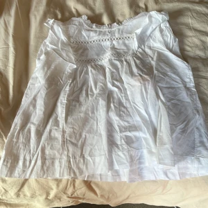 Vit blus med spets från Gina Tricot - Supersöt vit blus från Gina Tricot i storlek 146/152. Blusen har puffärmar, volang vid halsen och fina spetsdetaljer över bröstet. Tillverkad i bomull, perfekt för en fräsch och luftig look. Andvänd helst inte köp direkt knappen 🥰