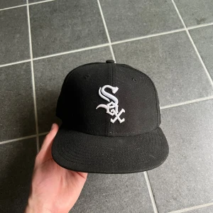 Svart New Era 59FIFTY White Sox keps - Snygg svart keps från New Era 59FIFTY med Chicago White Sox-logga broderad i vitt framtill. Klassisk rak skärm och broderad New Era-logga på sidan. Tillverkad i bomull och polyester, perfekt för dig som gillar sportig streetstyle.