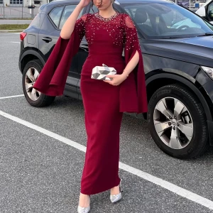 Vinröd långklänning med pärldetaljer - Supersnygg vinröd långklänning med capeärmar och pärldetaljer över axlar och bröst. Storlek 38, använt endast en gång i tre timmar och som ny! Klänningen har en figurnära passform och transparent mesh upptill. Perfekt för dig som vill sticka ut med en elegant och unik look.