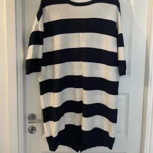 Randig kofta från Gina Tricot - Säljer en oversized kofta från Gina Tricot i storlek L. Den har breda marinblå och vita ränder, v-ringning och knappar framtill. Koftan har kortare ärmar och är stickad i ett mjukt material. Perfekt för lager-på-lager och chill vibes.