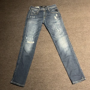 Blå jeans från Replay Hyperflex - Snygga blå Replay Hyperflex jeans i modellen Anbass. De har en slim fit passform och är dekorerade med slitningar för en trendig look. Perfekta för dig som vill ha stil och komfort i ett.