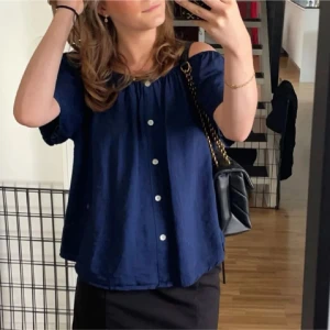Marinblå offshoulder blus med knappar - Säljer en marinblå blus med offshoulder och korta ärmar. 