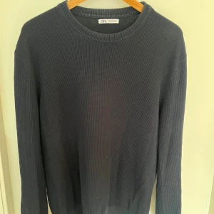 Svart stickad tröja från Zara - En stilren svart stickad tröja från Zara i storlek M. Tröjan har rund halsringning, ribbade muddar och lång ärm. Perfekt för dig som gillar en enkel och clean look med en klassisk passform.