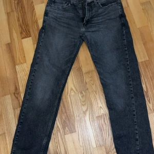 Levi's 505 svarta jeans W32 L34 - Svarta Levi's 505 jeans med klassisk femficksdesign och rak passform. Jeansen har en mörk tvätt och är tillverkade i slitstarkt denim med dragkedja i gylfen. Perfekt för dig som gillar en tidlös look och vill ha jeans som funkar till allt.