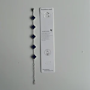 Navy-silver alhambra bracelet  - Snyggt armband i rostfritt stål med fem blå fyrklöverformade hängen. Kedjan är silverfärgad och har justerbar längd. Perfekt för dig som gillar unika detaljer och vill addera lite färg till din stil. Mvh clover.se