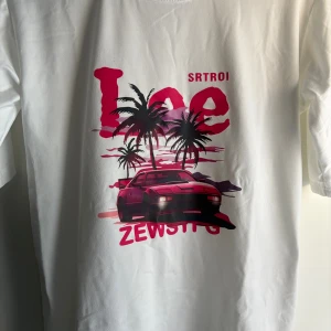 Vit t-shirt med retro biltryck - Vit t-shirt med coolt tryck av en röd sportbil, palmer och rosa solnedgång. Stora röda bokstäver och texten 'ZEWSYFG' framtill. Skön passform och klassisk rund hals. Perfekt för dig som gillar streetstyle och retro vibes.