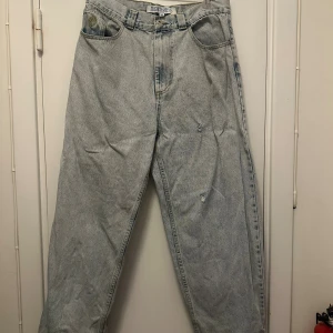 Big Boy ljusblå baggy jeans  - Ljusblå baggy jeans från Big Boy med råa, fransiga benslut och klassisk femficksdesign. Jeansen har hög midja och bred passform, tillverkade i slitstark denim. Perfekt för dig som gillar en avslappnad och streetig stil.