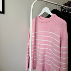 Rosa randig stickad tröja Lager157  - Superfin rosa stickad tröja från lager157 i storlek S. Tröjan har vita horisontella ränder, rund halsringning och breda ribbade muddar vid ärmslut och nederkant. Perfekt för dig som gillar en söt och avslappnad stil. Använd 1-2 gånger.