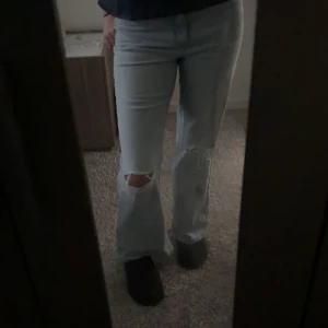 Ljusblå ripped jeans med raka ben/lite utsvängda  - Säljer ett par ljusblå jeans med raka ben/lite utsvängda beror på hur den passar en. Och slitningar vid knäna. Jeansen har klassisk femficksdesign och är tillverkade i denim. Snyggt avslappnad passform och perfekt för dig som gillar en trendig streetstil.