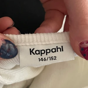 Vit ribbad långärmad topp Kappahl - Säljer en vit, ribbad långärmad topp från Kappahl i storlek 146/152. Toppen har en croppad passform med bred, rundad halsringning och är tillverkad i mjuk bomull. Perfekt för dig som gillar en clean och enkel stil med lite edge.
