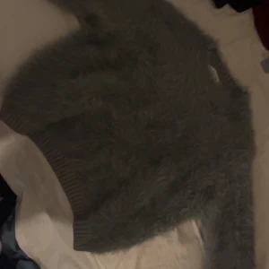 Mörkgrön fluffig stickad tröja - Supermjuk och fluffig mörkgrön stickad tröja med långa ärmar och bred ribbad mudd nertill. Perfekt för dig som vill ha en mysig och trendig look under kyliga dagar. Den är kort vid magen men varm