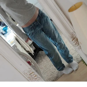 Blå Lee jeans med loose fit - Säljer ett par klassiska blå jeans från Lee med loose fit och raka ben. Jeansen har låg midja, fem fickor och snygga slitningar för en avslappnad vibe. Tydlig Lee-logga på bakfickan och läderpatch i midjan. Perfekta för dig som gillar en chill och tidlös stil.