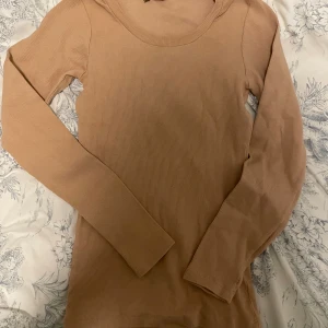 Beige ribbad långärmad tröja Fancy - Säljer en beige långärmad tröja från The Fancy For You. Tröjan är ribbad och har en rund halsringning. Perfekt för dig som gillar enkla och stilrena plagg med skön passform. Passar till jeans eller kjol och är lätt att matcha med andra färger.